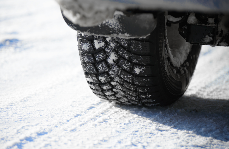 A close of a vehicle's tire during snowfall